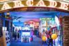 The entrance to the Arcade at Fun Mountain with several children running around and lots of different games with bright multicolor lights.