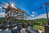 An outdoor ropes course with a seating area below it and the lush green Ozark mountains in the background on a sunny day at Fun Mountain at Big Cedar Lodge.