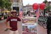 A person wearing a harvard hat and a purple shirt with "HAHVAH" printed on it standing beside a Harvard poster during The Harvard Tour with Go City - Boston All-Inclusive Pass.
