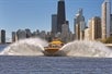 A yellow speedboat on the water with a city skyline in the background during a Lakefront Speedboat Tour in Chicago.
