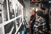 A group of people standing indoors, looking at a poster on a wall that appears to be related to an art exhibition at the Rature Gallery, featuring the artist Haiyg Eteclerc at the American Writers Museum in Chicago.
