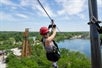 A person wearing an outdoor clothing and a climbing helmet, ziplining at the Forge Adventure Park in Illinois.