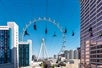 Several people ziplining with a big high roller observation wheel as a backdrop at Fly LINQ Las Vegas with Go Las Vegas Explorer Pass.
