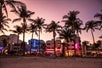 Various building by the beach lit by colorful lights on an Art Deco Tour with Go Miami All-Inclusive Pass.