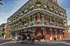 a horse carriage on a street with the French Quarter in the background. It captures an outdoor scene with a historical and cultural feel, showcasing a horse-drawn vehicle amidst city buildings and streets.