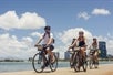 A group of cyclists enjoying a ride along a scenic waterfront path in Hawaii, showcasing a vibrant and active outdoor lifestyle.