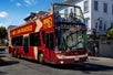 Double decker red bus by Big Bus San Francisco with several people aboard touring around Haight-Ashbury district in San Francisco with Go San Francisco Explorer Pass.