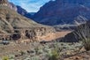 Two Maverick helicopters in the canyon next to the red brown water of Lake Mead with tourists taking photos of the reservoir.