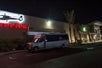 A small bus parked outside the Maverick terminal with their logo glowing on the side of the building.