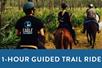 People riding horses on a dirt trail and a box saying "1-Hour Guided Trail Ride" with Guided Horseback Trail Ride in Orlando, Florida, USA.