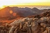 The rock-covered mountains with the sun rising behind them on the Haleakala Sunrise Tour in Wailuku Hawaii, USA.