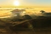 The sun just above the horizon shining down on some mountains on the Haleakala Sunrise Tour in Wailuku Hawaii, USA.