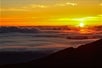 The sun peaking above the clouds and they move over the mountains on the Haleakala Sunrise Tour in Wailuku Hawaii, USA.