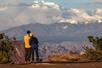 A couple overlooking Shafer Trail on a tour of the Island in the Sky district of Canyonlands National Park with clouds in the distance.