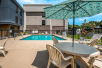 Outdoor pool area with sun loungers, table and chairs.