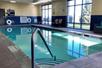 A small indoor swimming pool with large windows on the right side and chairs scattered around it at the Hampton Inn in Minneapolis, Minnesota.