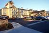 The exterior and parking lot of the Hampton Inn Ukiah with a clear sky and the sun shining down on the hotel.