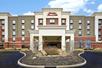 The front entrance to the Hampton Inn & Suites Columbus-Easton Area on a bright day with clouds in the sky.