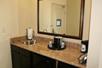 A hotel room sink with a mirror hanging over it and a coffee maker and ice bucket on the counter next to it.