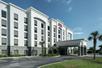 The front exterior and covered entrance of the Hampton Inn & Suites Panama City Beach-Pier Park Area on a sunny day.