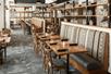 A large dining room with brown tables and chairs and shelves with glassware dividing the room at the Territory Kitchen & Bar.