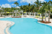 An outdoor pool surrounded by palm trees, cabanas and lounge chairs at Hilton Garden Inn Key West.