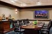 Meeting facility with a large table, executive chairs, flat-screen TV and snacks.