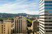 Wide shot of the city of Portland with trees in the distance and a blue cloudy sky overhead on a bright sunny day.