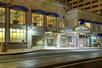 Street view of the beige stone exterior and front entrance to the Hilton Portland Downtown with blue awnings over the windows at night.