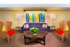 Lobby seating area with a colorful sofa, painting and chairs.