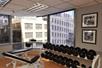 A fitness center with free weights and a bench along a wall with large windows with a view of the city in Denver, Colarado.