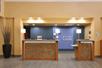 The well lit wood and stone front desks at the Holiday Inn Express Flagstaff with a dusty blue wall behind them.