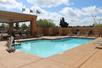 A light blue outdoor swimming pool with lounge chairs lining the sides and a blue cloudy sky overhead at the Holiday Inn Express Flagstaff.