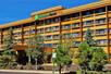 The exterior of the Holiday Inn Express Flagstaff with a covered entrance and trees in the landscaping on a sunny day.
