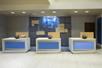 Three blue and white front desks with a geometric wall with the logo for the Holiday Inn Express on it behind them.