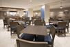 A large dining room with dark brown tables with brown and blue chairs at them at the Holiday Inn Express Salt Lake City Downtown.