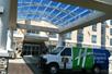 The shuttle for the Holiday Inn Express & Suites Columbus parked under the covered entrance to the hotel on a sunny day.