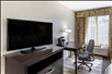 Guest room with a flat-screen TV and work desk with lamp.