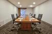 Meeting facility with a long wooden table and executive leather chairs.