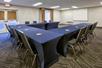 Meeting facility equipped with chairs, long tables, and a white projector screen.
