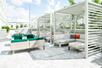 An outdoor lounge area with covered couches on the left and green chairs sitting in the sun on right at Holiday Inn & Suites.