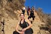 Several women in hiking clothes standing on different levels of a rocky path posing for a photo on a sunny day.