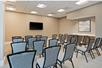A conference room with rows of gray chairs lined up in front of a TV on the fall wall at the Homewood Suites By Hilton Panama City Beach.
