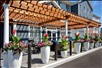 Enjoy a relaxing afternoon or morning in the outdoor patio with seating area and beautiful potted flowers under a pergola.