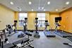 A fitness facility with yellow walls and a row of different cardio equipment and a weight machine at the Homewood Suites by Hilton New Braunfels.