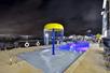 An outdoor pool with a kids play ear at night with blue lights illuminating the water at the Homewood Suites by Hilton New Braunfels.