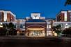 The front covered entrance to the Homewood Suites with trees on both sides at night with a clear sky overhead.