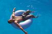 A man in a blue inflatable tube while floating along the Castaway Creek lazy river on a sunny day.