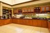 A room with green walls and a brown cabinets lining three sides with a breakfast bar spread across them and smaller cabinets overhead.