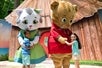 A young girl and a boy joyfully meet two life-sized character mascots, Snip, a white and gray cat on the left, and Daniel Tiger's mascot on the right at Idlewood.